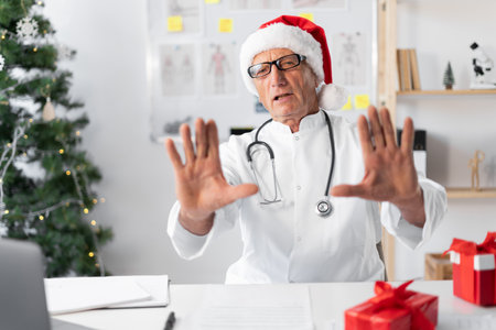 unimpressed Senior elderly Doctor in Santa hat on the shift on christmas eve refuses something, say no, rejects proposalの写真素材