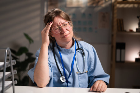 unhealthy physician nurse suffering headache migraine working over hours in hospital office on night shift. Medicine and Health care serviceの写真素材