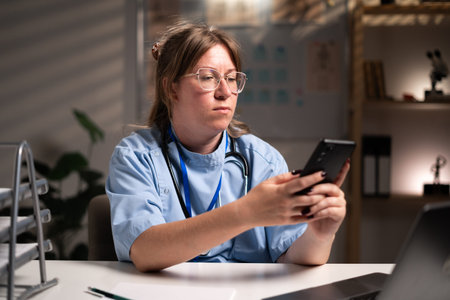 physician nurse using smartphone chatting message working over hours in hospital office on night...
