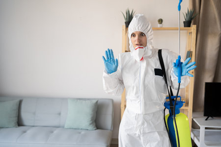 Shocked amazed Female exterminator from pest control service working inside house with sprayer bottle at homeの写真素材