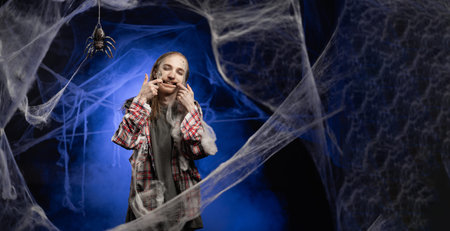 Dead guy with horrible scary Halloween zombie makeup on face holds fingers at edge of lips forces...