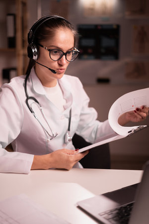 Telemedicine, medicine and healthcare concept. female doctor or nurse with headset having video call working on night shift at hospitalの写真素材
