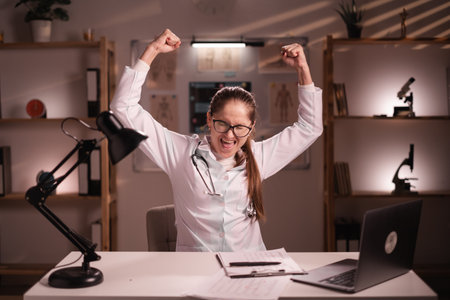 excited medical doctor woman celebrating win and success while working on night shift in the hospital or clinic officeの写真素材