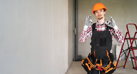 male laborer, builder or repairman wearing helmet and tool belt ready for repairing or building...