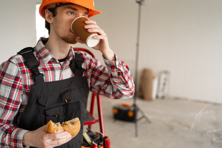 construction worker or repairman drinks coffee during a break on workplace