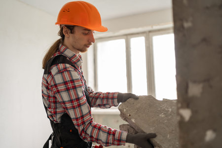 House Renovation concept. Worker taking off old stones materials