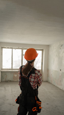 Rear view of Construction worker wearing hard hat performing tasks in apartmentの写真素材