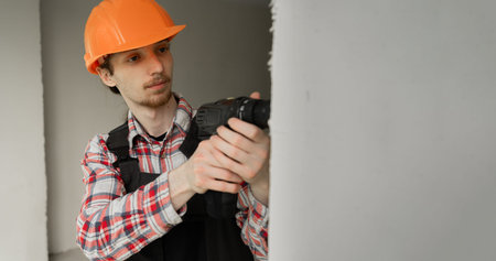 Builder worker or repairman in hardhat working on construction site with pneumatic hammer drill...