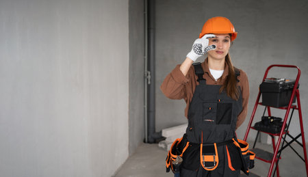 Woman Builder. Female Architect pointing fingers gesture small measure size in unfinished building. repair, construction and building concept. banner.の写真素材