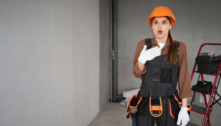Woman Builder. Female Architect pointing finger at herself, oh my gosh, who me gesture in unfinished building. repair, construction and building concept.の写真素材