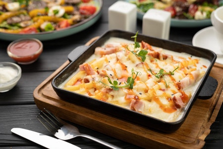 Hot skillet of baked potatoes with crispy bacon and creamy sauce, perfect for restaurant menuの写真素材