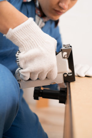 Female Carpenter assembly furniture using a construction stapler to fixの写真素材