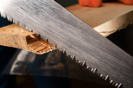 Close-up of carpenters hand saw cutting wood board working in carpenter shop.の写真素材