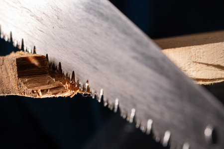 Close-up of carpenters hand saw cutting wood board working in carpenter shop.の写真素材