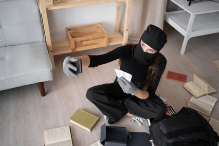 Thief in black balaclava. Female Robber entering a house for stealing making selfie portrait with moneyの写真素材