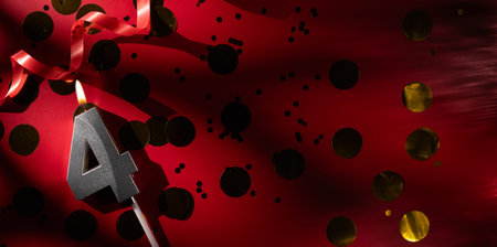 Concept of celebrating birthday and anniversary. Number 4 four silver celebration birthday candle on festive red background with large golden confetti. Four years birthday.の写真素材