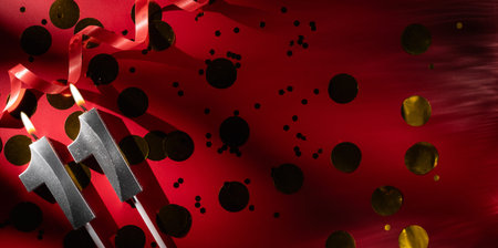Concept of celebrating birthday and anniversary. Number 11 eleven silver celebration birthday candle on festive red background with large golden confetti. Eleven years birthday.の写真素材
