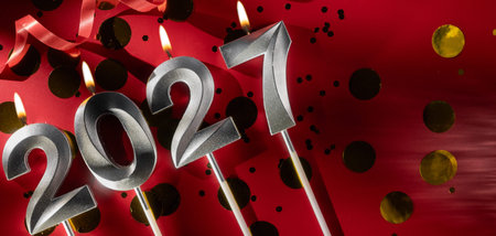 Happy New Year 2027. Numbers 2027 silver candles on red holiday background with confetti. Space for textの写真素材