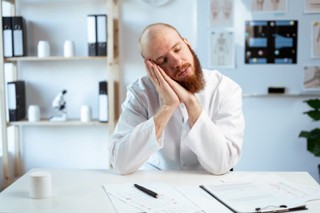 Overworked Bearded male doctor with prescriptions, medication documents sleeping on workplace in...