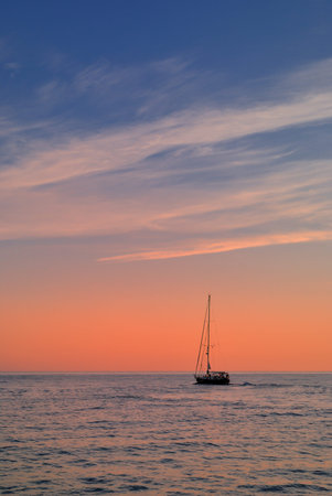 A boat is sailing away from the port of Chania in Crete at sunrise