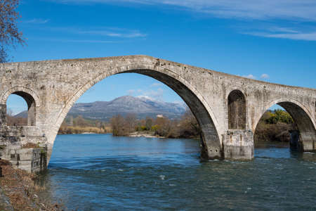 Bridge of Arta in Greece. A stone bridge that crosses the Arachthos river in the west of the city of Arta. It has been rebuilt many times over the centuries, starting with Roman or perhaps older foundations; the current bridge is probably a 17th-century Ottoman construction. The folk ballad The Bridge of Arta tells a story of human sacrifice during its buildingの写真素材