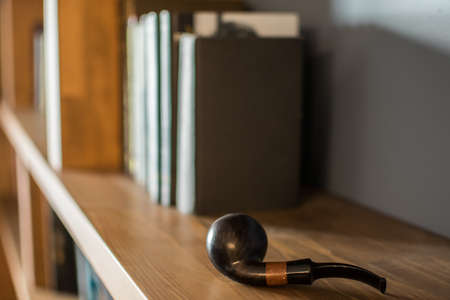 Smoking pipe on a bookshelfの写真素材
