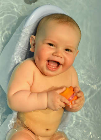 infant boy with a smile bathed in a water bathの写真素材