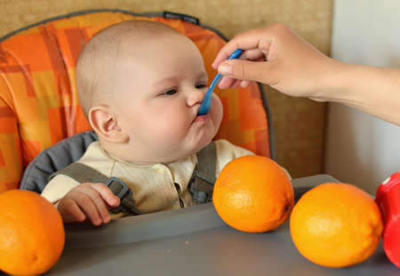 Mum feeds from the spoon infant boyの写真素材