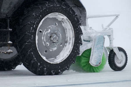 tractor with big wheels removes snow in snowfallの写真素材