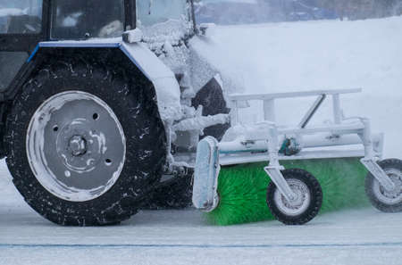 tractor with big wheels removes snow in snowfallの写真素材