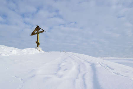 A large Orthodox cross on a snow-covered hill on a winter dayの写真素材