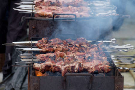 Barbeque sticks with meat, on the grill and heavy smoke above brazier.の写真素材