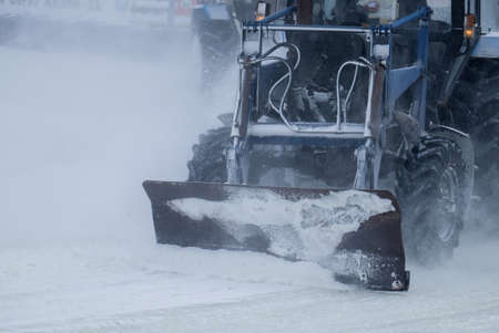 tractor with big wheels removes snow in snowfallの写真素材