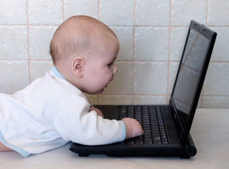 Little boy aged three months and simulates on a laptopの写真素材