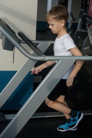 Portrait of a boy seven years on the treadmill in the gymの写真素材
