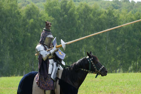 Medieval knight in metal armor on a horse in a fieldの写真素材