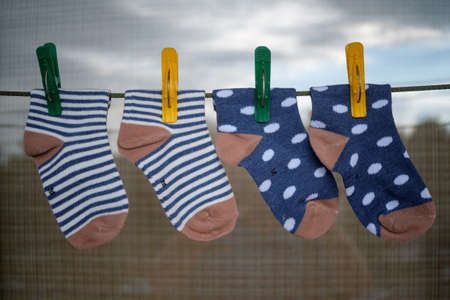 Baby socks after washing on a string with colorful clothespinsの写真素材