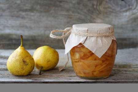 fresh pears and pear jam in a glass jar on a wooden Boardの写真素材