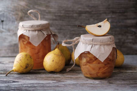 fresh pears and pear jam in a glass jar on a wooden Boardの写真素材