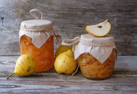 fresh pears and pear jam in a glass jar on a wooden Boardの写真素材