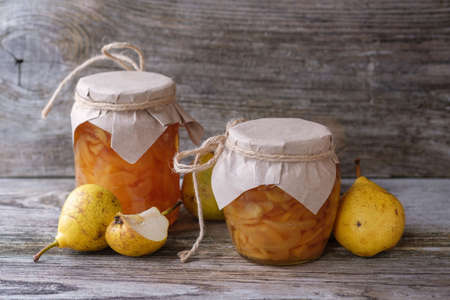 fresh pears and pear jam in a glass jar on a wooden Boardの写真素材