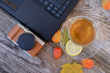 laptop, stylish, mirrorless camera and green lemon tea in glass Cup on old wooden tableの写真素材