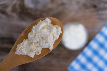 wooden spoon with fresh country cottage cheese on the table. the view from the top