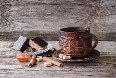 black coffee in a big ceramic mug , pieces of chocolate waffle cake rolls cinnamon on a old wooden Boardの写真素材