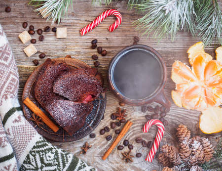 Christmas still life with a mug of coffee, Mandarin, chocolate cake, sweater, candy, pine cones, pine branches on a wooden table. the view from the topの写真素材
