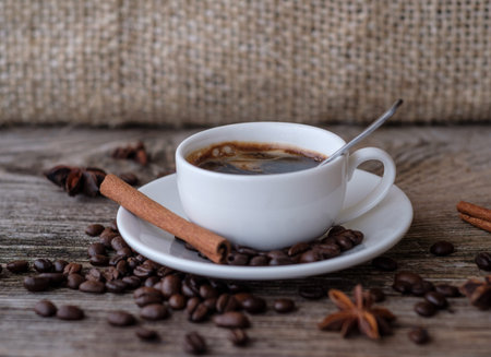 black coffee in a white Cup on a wooden table with coffee beans , cinnamon and aniseの写真素材