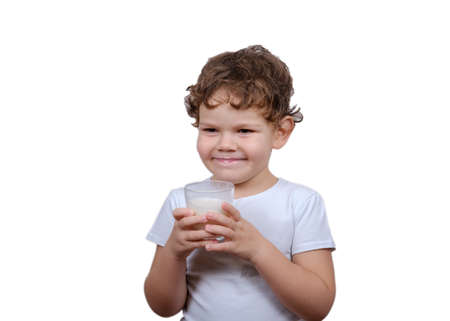 cute curly-haired European boy drinking milk from a glass Cup. the isolated image on a white backgroundの写真素材