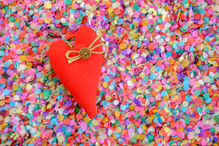 red heart made of fabric handcrafted in the background of multi-colored paper confetti. decor Valentine's dayの写真素材