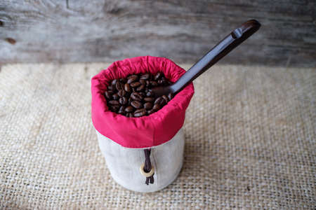 coffee beans on burlap, a small pouch and a wooden spoonの写真素材