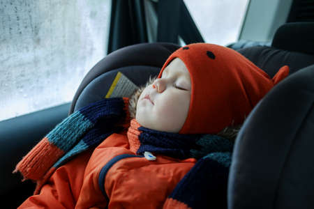 European boy sleeping in the car seat in the car in the winter in clothesの写真素材